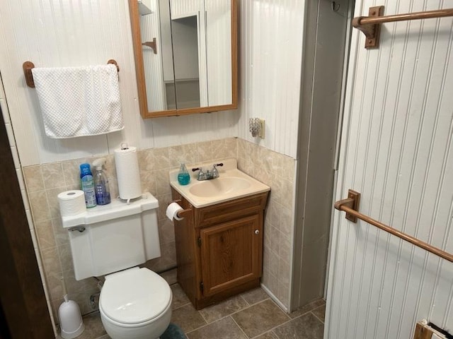 bathroom with vanity, tile walls, and toilet