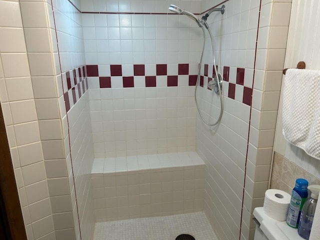 bathroom featuring tiled shower and toilet