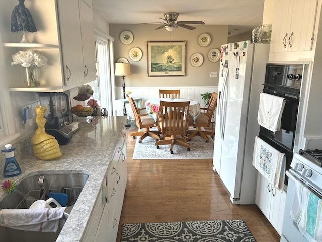 kitchen with sink, white cabinetry, light stone counters, dark hardwood / wood-style flooring, and white appliances