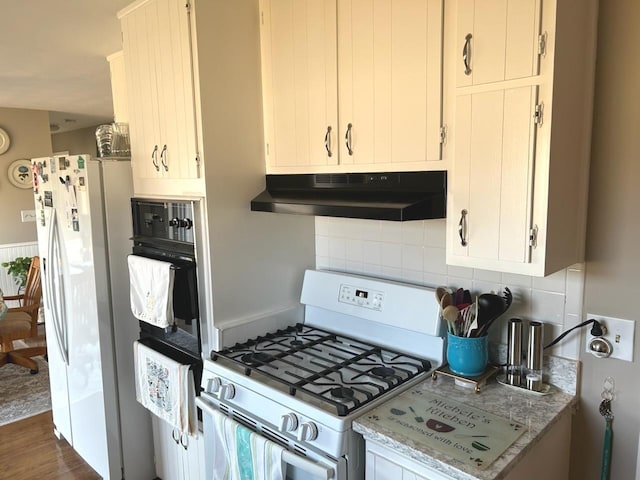 kitchen with white appliances, white cabinetry, light stone counters, tasteful backsplash, and dark hardwood / wood-style flooring