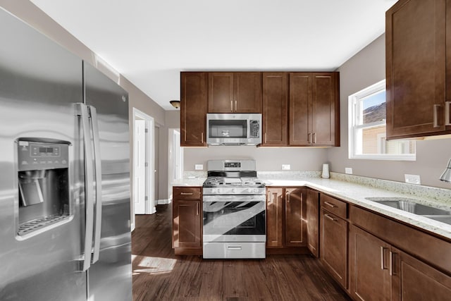 kitchen featuring light stone counters, appliances with stainless steel finishes, dark hardwood / wood-style floors, and sink