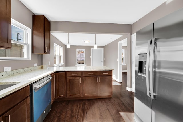 kitchen with pendant lighting, dark hardwood / wood-style flooring, kitchen peninsula, and appliances with stainless steel finishes