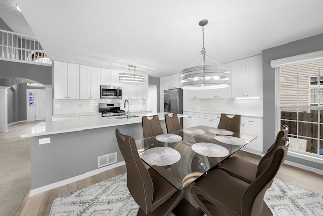 dining room featuring sink, a chandelier, and light hardwood / wood-style flooring