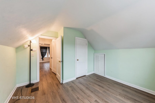 additional living space with lofted ceiling and hardwood / wood-style flooring