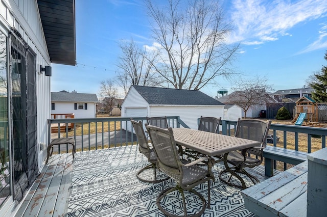 deck with a garage, an outbuilding, and a playground