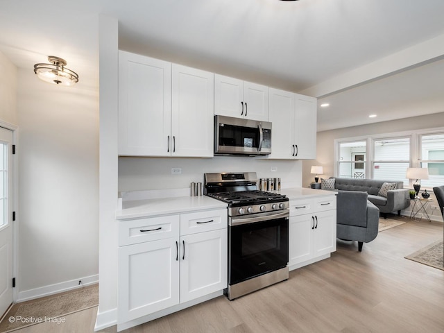 kitchen featuring appliances with stainless steel finishes, light hardwood / wood-style floors, and white cabinets