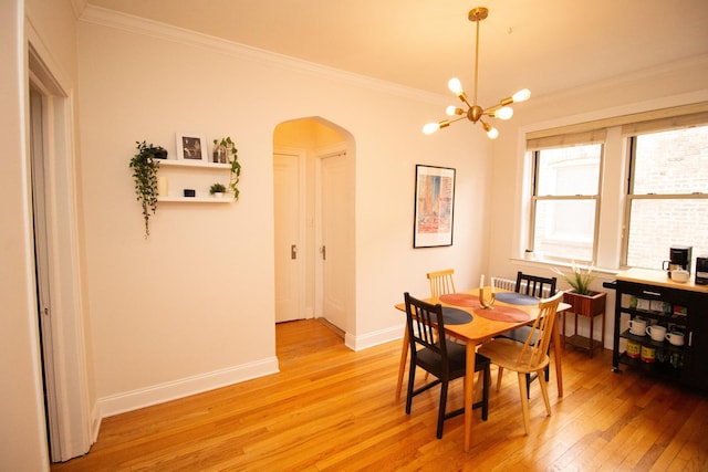 dining area with an inviting chandelier, ornamental molding, and light hardwood / wood-style floors