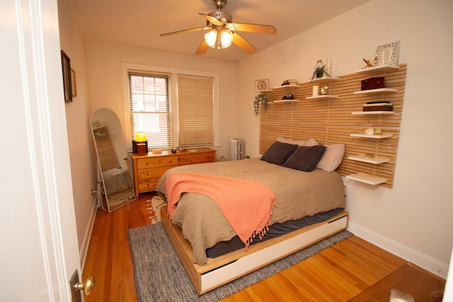 bedroom with ceiling fan, dark hardwood / wood-style floors, and radiator