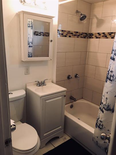 full bathroom with shower / bathtub combination with curtain, vanity, and toilet