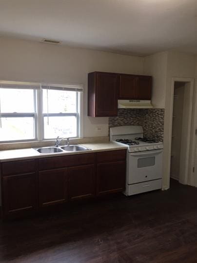 kitchen featuring sink, dark hardwood / wood-style flooring, decorative backsplash, dark brown cabinetry, and white gas stove