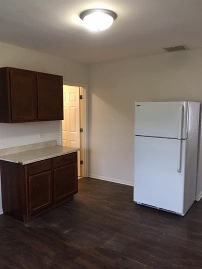 kitchen with white refrigerator, dark brown cabinets, and dark hardwood / wood-style flooring