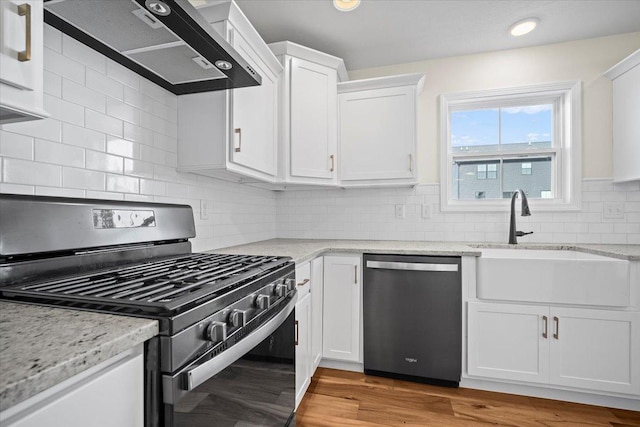 kitchen featuring sink, dishwasher, gas range oven, white cabinets, and wall chimney exhaust hood