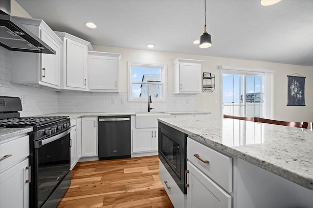 kitchen with white cabinetry, wall chimney exhaust hood, hanging light fixtures, and black appliances