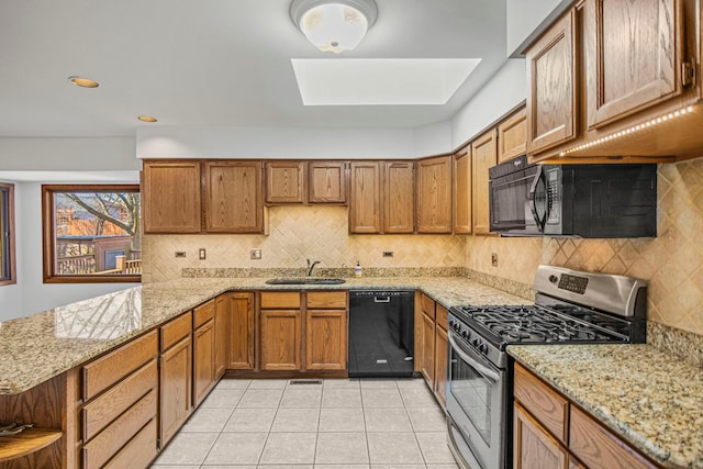 kitchen with brown cabinetry, a sink, a peninsula, and black appliances