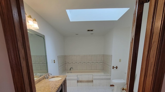 bathroom featuring a skylight, vanity, toilet, tiled tub, and tile patterned floors