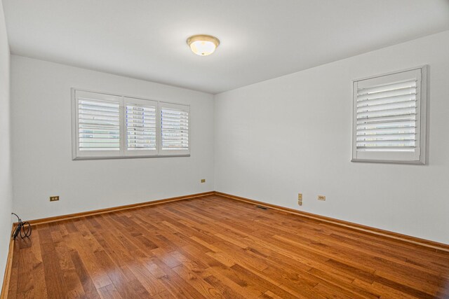 unfurnished bedroom with hardwood / wood-style flooring and multiple closets