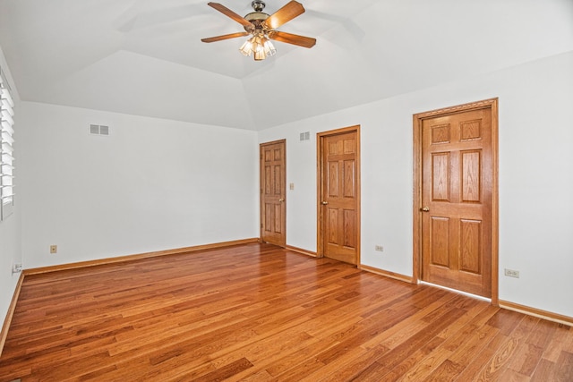 unfurnished bedroom featuring vaulted ceiling, light wood-style flooring, visible vents, and baseboards