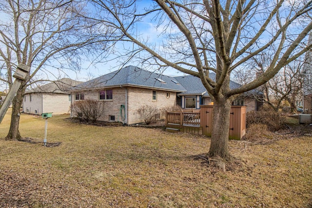 rear view of house featuring brick siding, a lawn, a shingled roof, and a wooden deck