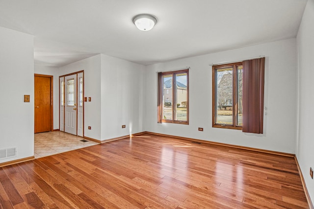 unfurnished room with wood finished floors, visible vents, and baseboards