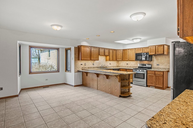 kitchen featuring brown cabinets, backsplash, stainless steel appliances, and a sink