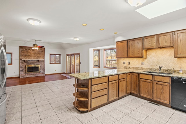 kitchen featuring a brick fireplace, light tile patterned flooring, dishwasher, and a sink