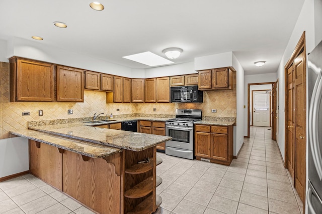 kitchen with brown cabinets, a sink, a peninsula, and black appliances