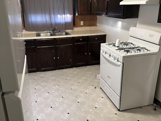 kitchen featuring dark brown cabinetry, white gas range, and sink