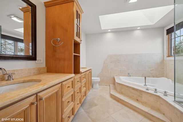 bathroom featuring a relaxing tiled tub, vanity, a skylight, and toilet