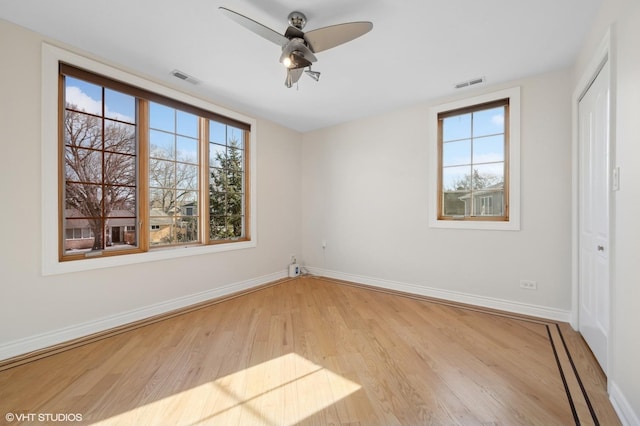 interior space with multiple windows, ceiling fan, light wood-type flooring, and a closet