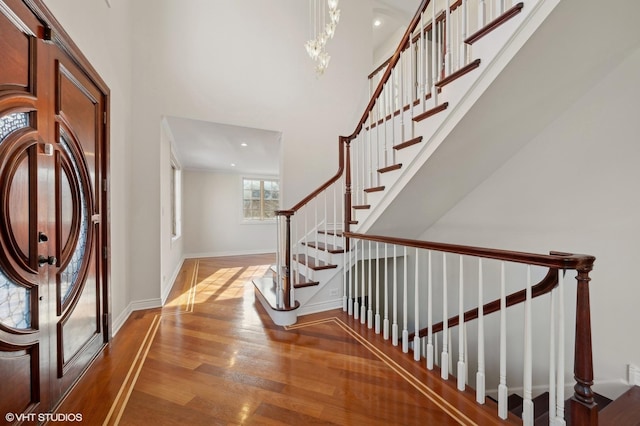 entryway featuring a towering ceiling and wood-type flooring