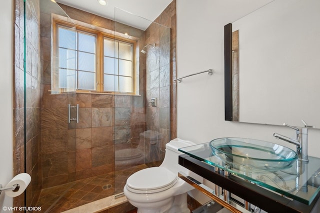 bathroom featuring toilet, a shower with door, and sink