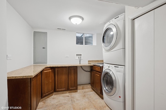 washroom with cabinets, stacked washer / dryer, electric panel, and light tile patterned floors