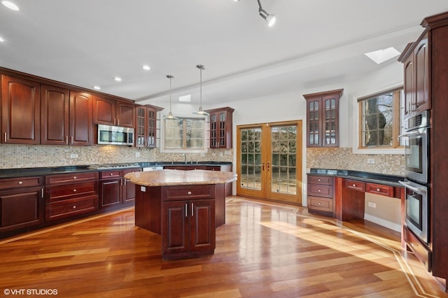 kitchen featuring pendant lighting, light hardwood / wood-style flooring, stainless steel appliances, tasteful backsplash, and a kitchen island