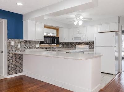 kitchen featuring light hardwood / wood-style floors, white cabinets, white appliances, and kitchen peninsula