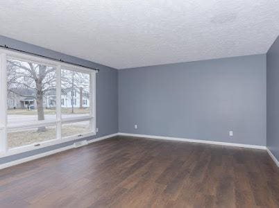 spare room featuring dark wood-type flooring and a textured ceiling