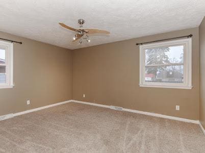 spare room featuring ceiling fan, light carpet, and a textured ceiling