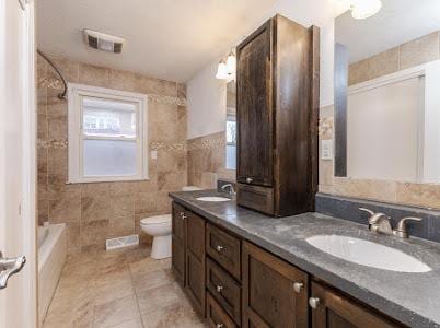 full bathroom featuring tub / shower combination, tile walls, tile patterned flooring, vanity, and toilet