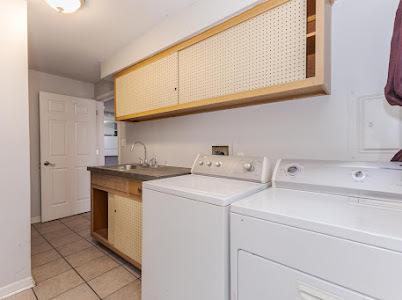 laundry area featuring cabinets, washing machine and clothes dryer, sink, and light tile patterned floors