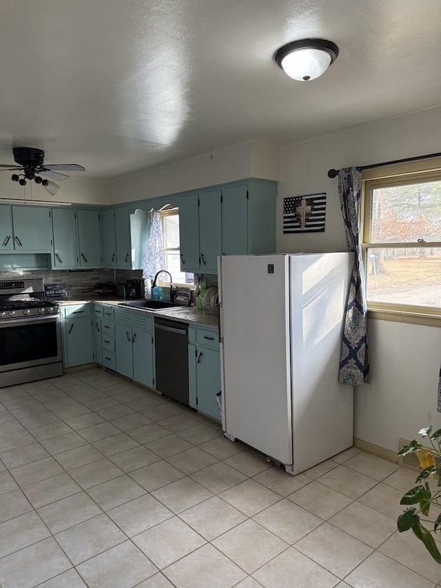 kitchen featuring dishwasher, sink, white fridge, ceiling fan, and stainless steel range with gas stovetop