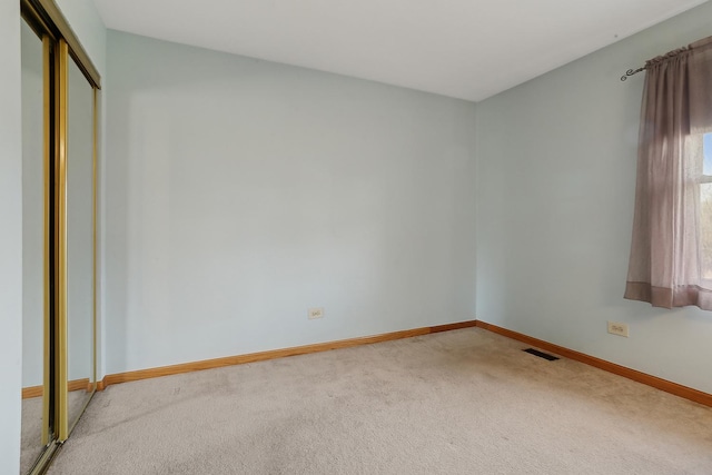 unfurnished bedroom with light colored carpet and a closet