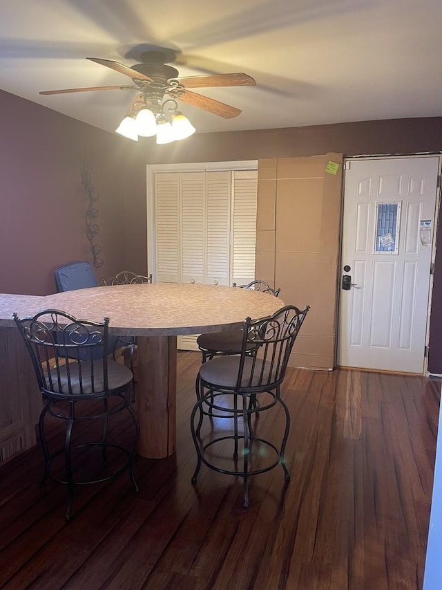 kitchen with dark hardwood / wood-style floors, a breakfast bar area, and ceiling fan