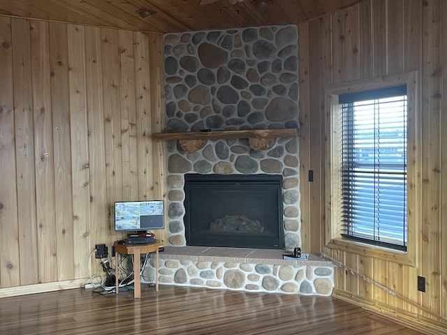 interior details featuring wood ceiling, a stone fireplace, wood walls, and hardwood / wood-style flooring