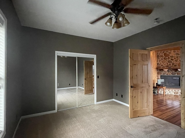 unfurnished bedroom with lofted ceiling, a stone fireplace, a closet, and ceiling fan