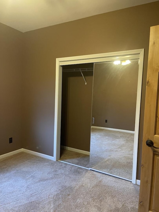 unfurnished bedroom featuring light carpet and a closet