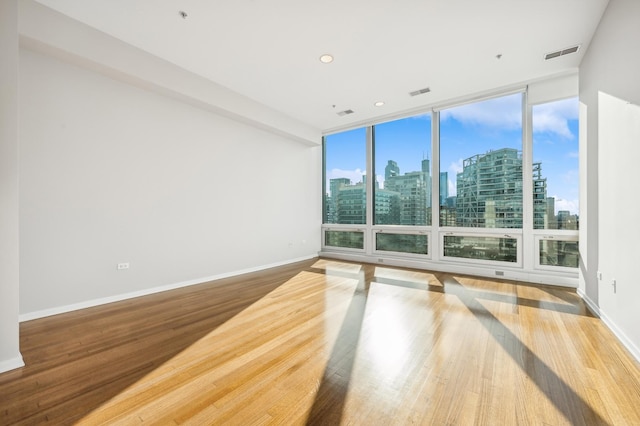 unfurnished room featuring a wall of windows and wood-type flooring