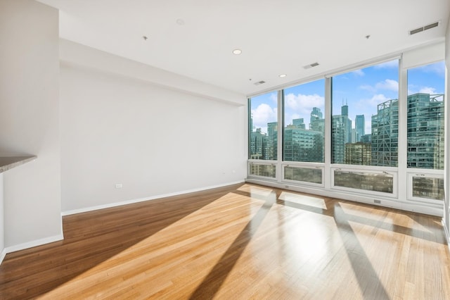 unfurnished room featuring hardwood / wood-style flooring and a wall of windows