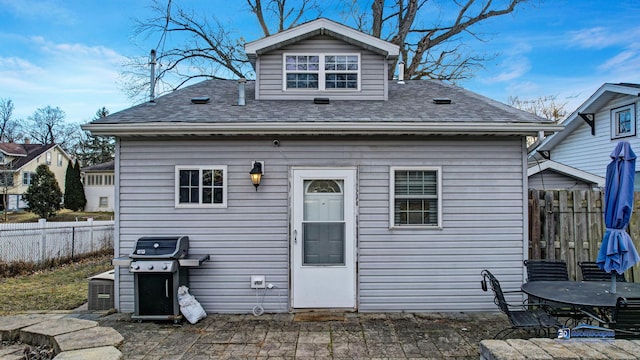 back of property featuring a shingled roof and fence