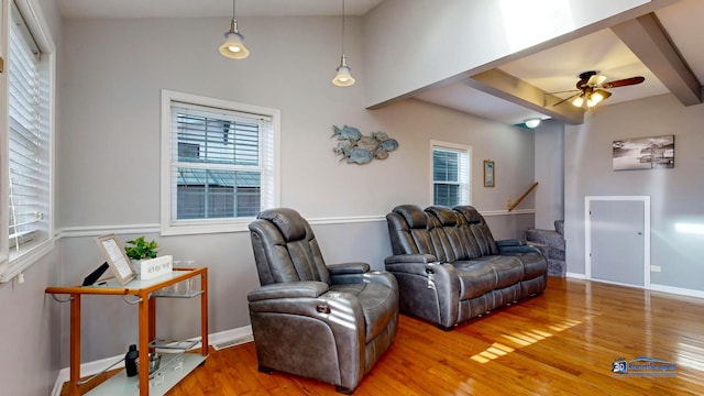 living area featuring beamed ceiling, ceiling fan, baseboards, and hardwood / wood-style flooring