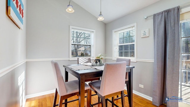 dining space with baseboards, lofted ceiling, and wood finished floors