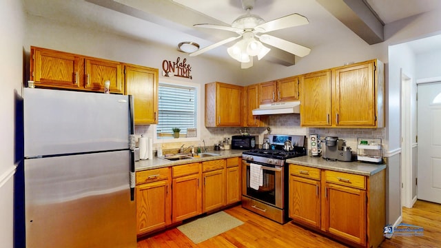 kitchen with under cabinet range hood, backsplash, appliances with stainless steel finishes, and a sink